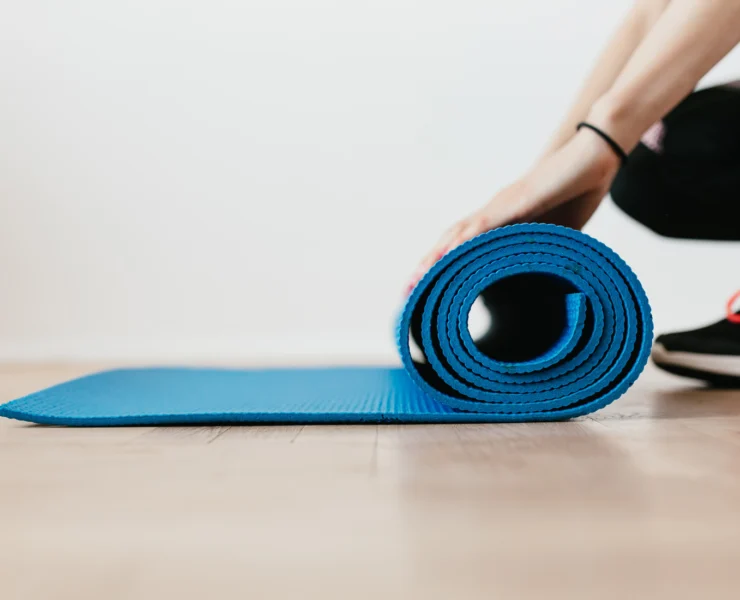 woman rolls up a yoga mat