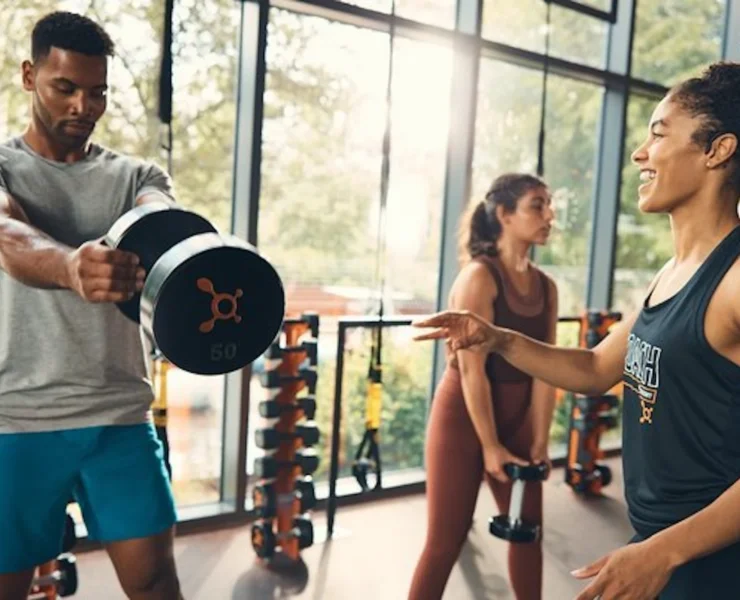 man lifts a dumbbell at an Orangetheory studio