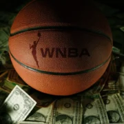 a WNBA branded basketball on top of various bills